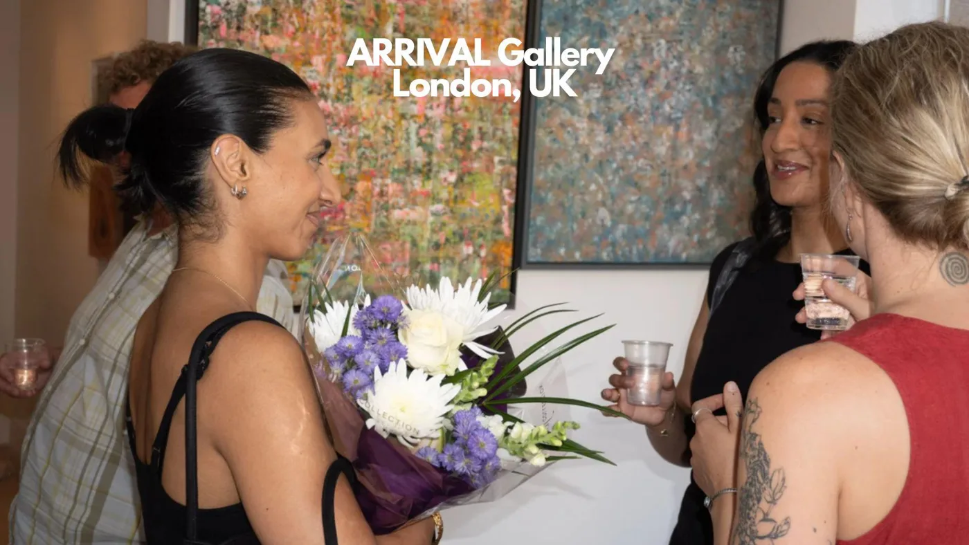 A woman holding a bouquet of white and purple flowers talks with two other women in front of large abstract paintings