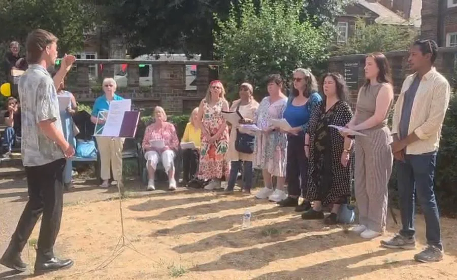 The Peabody Community Choir singing outdoors on a summer evening