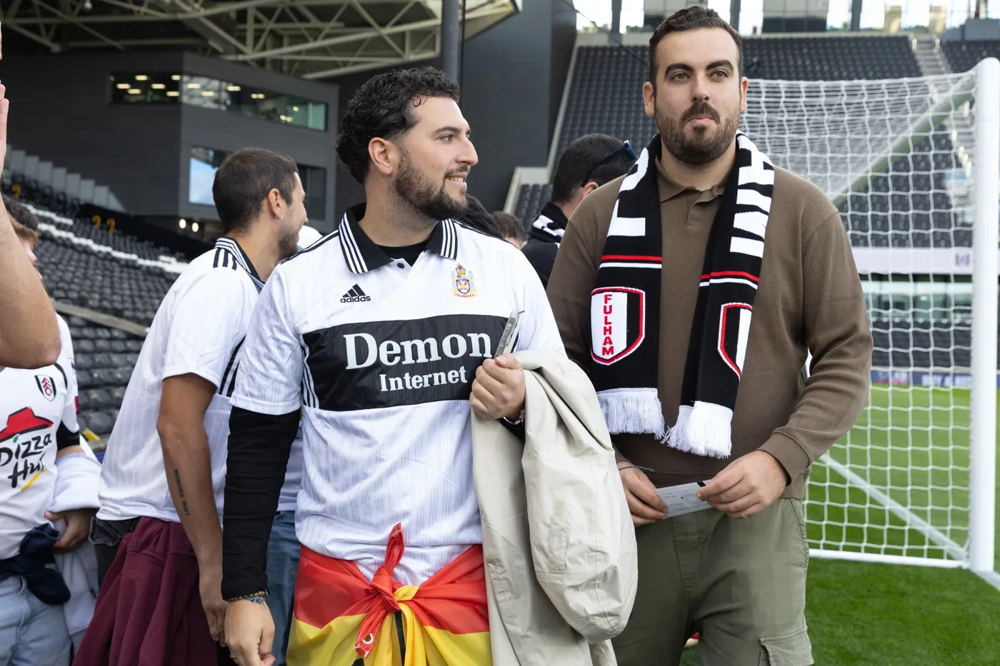 Two members of the group by the goal, one in a white Fulham shirt with a Spanish flag tied round his waist