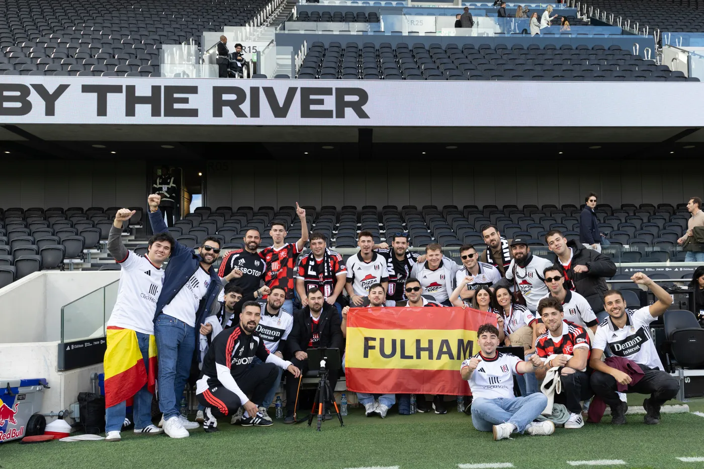 The group from Spain gathered on the pitch in front of a stand marked By the River with a red and yellow Fulham banner