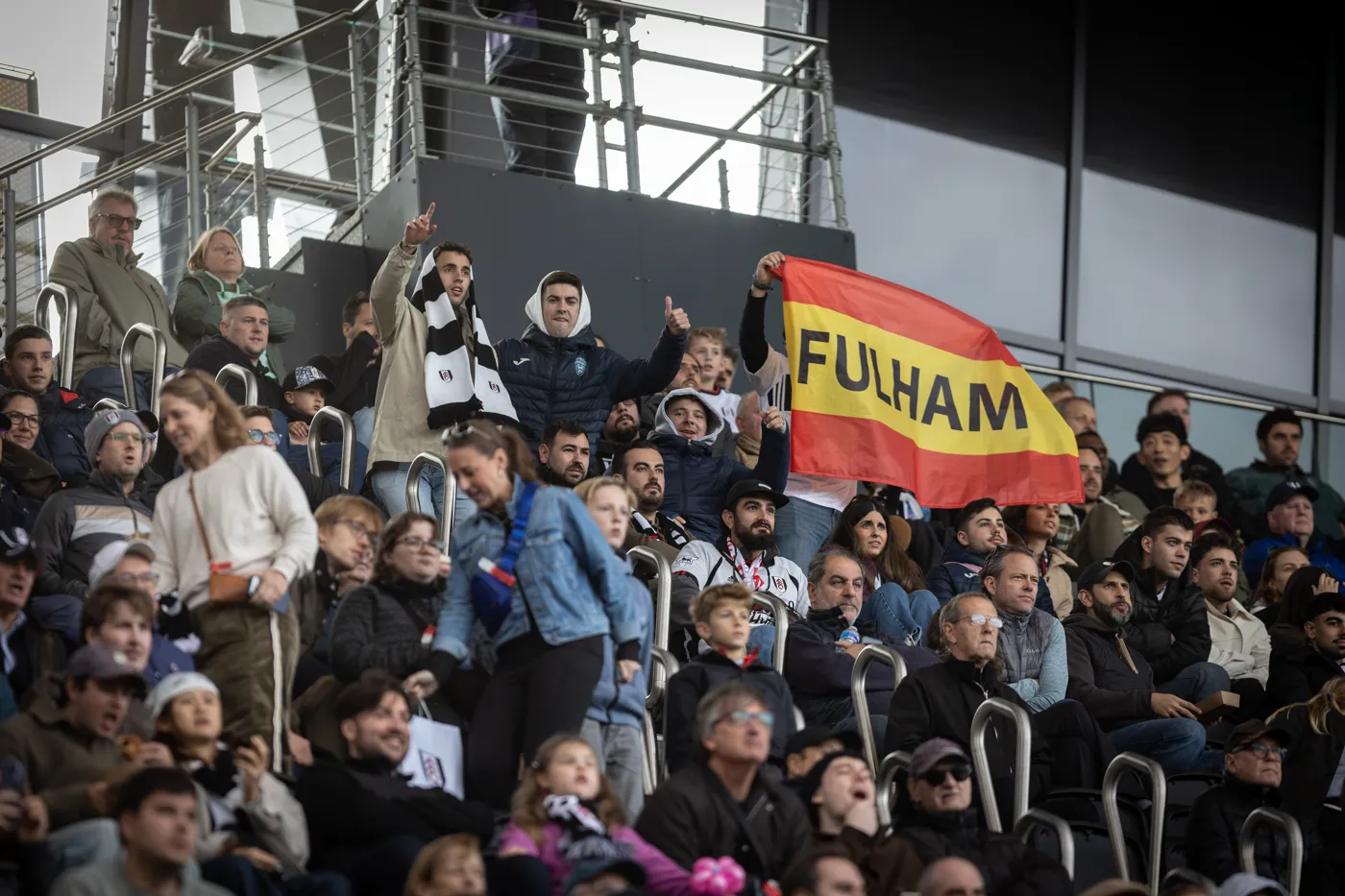 A fan in a white Gonzalo number 7 shirt holds a Spanish flag above his head in the stand