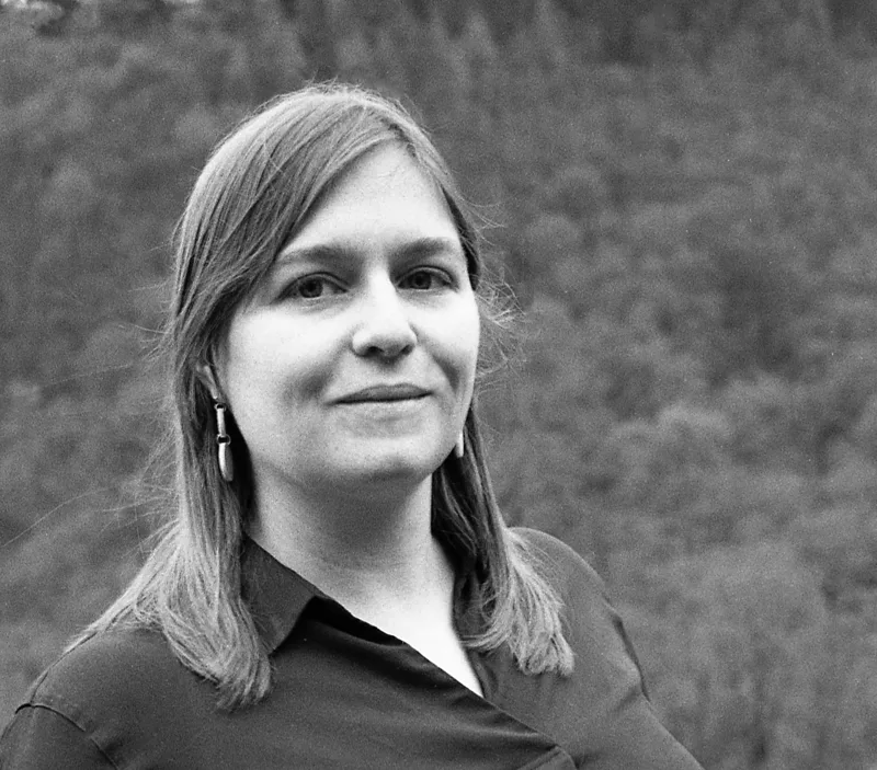 Black and white portrait of Naomi Elster with trees behind her