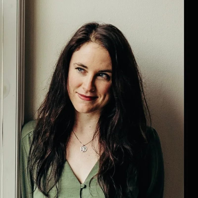Charlotte Newman, with long dark hair, leaning against a door frame