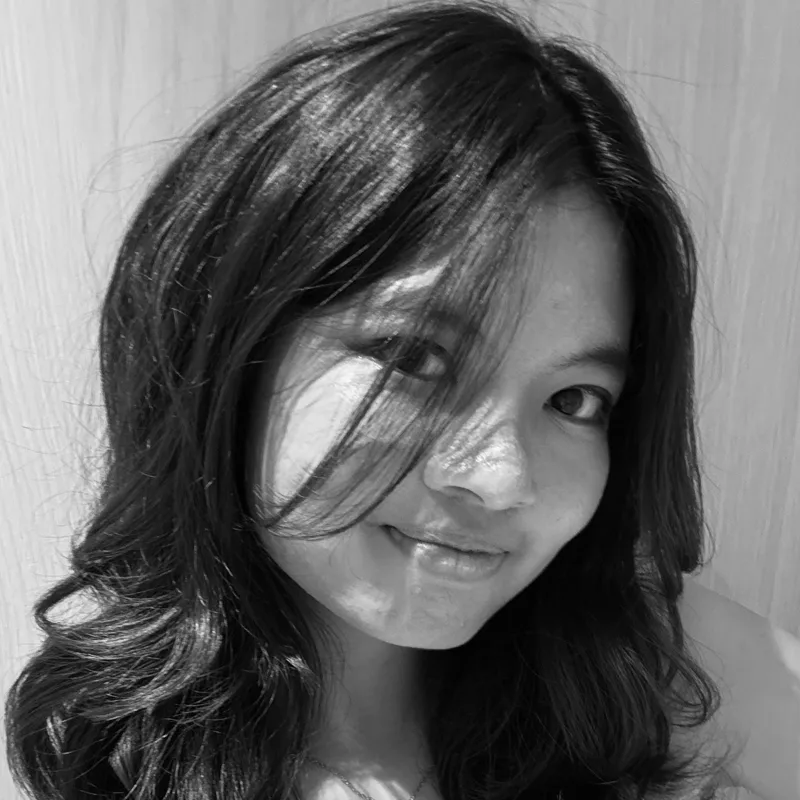 Black and white portrait of Felicia Ng, smiling, with hair across one side of her face