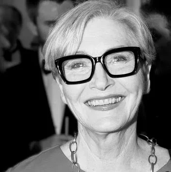 Black and white photograph of Melanie Wold, smiling, in large dark-framed glasses